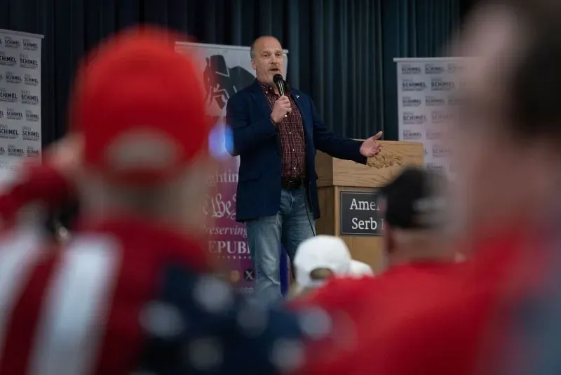 يتحدث براد شيمل، المرشح المحافظ في ويسكونسن، خلال فعالية انتخابية، بينما يستمع الحضور الذين يرتدون قبعات حمراء.