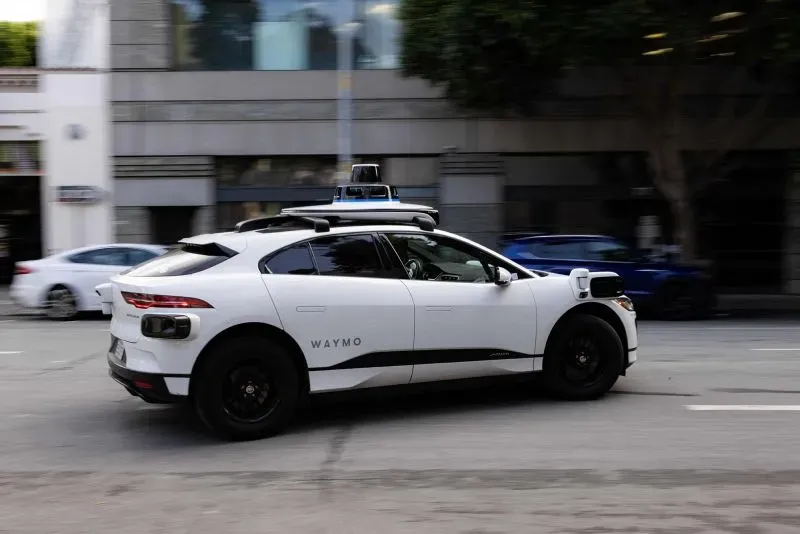 سيارة ذاتية القيادة من شركة وايمو تسير في شوارع مدينة أمريكية، مع التركيز على التكنولوجيا المتقدمة المستخدمة في خدمات التاكسي الآلي.