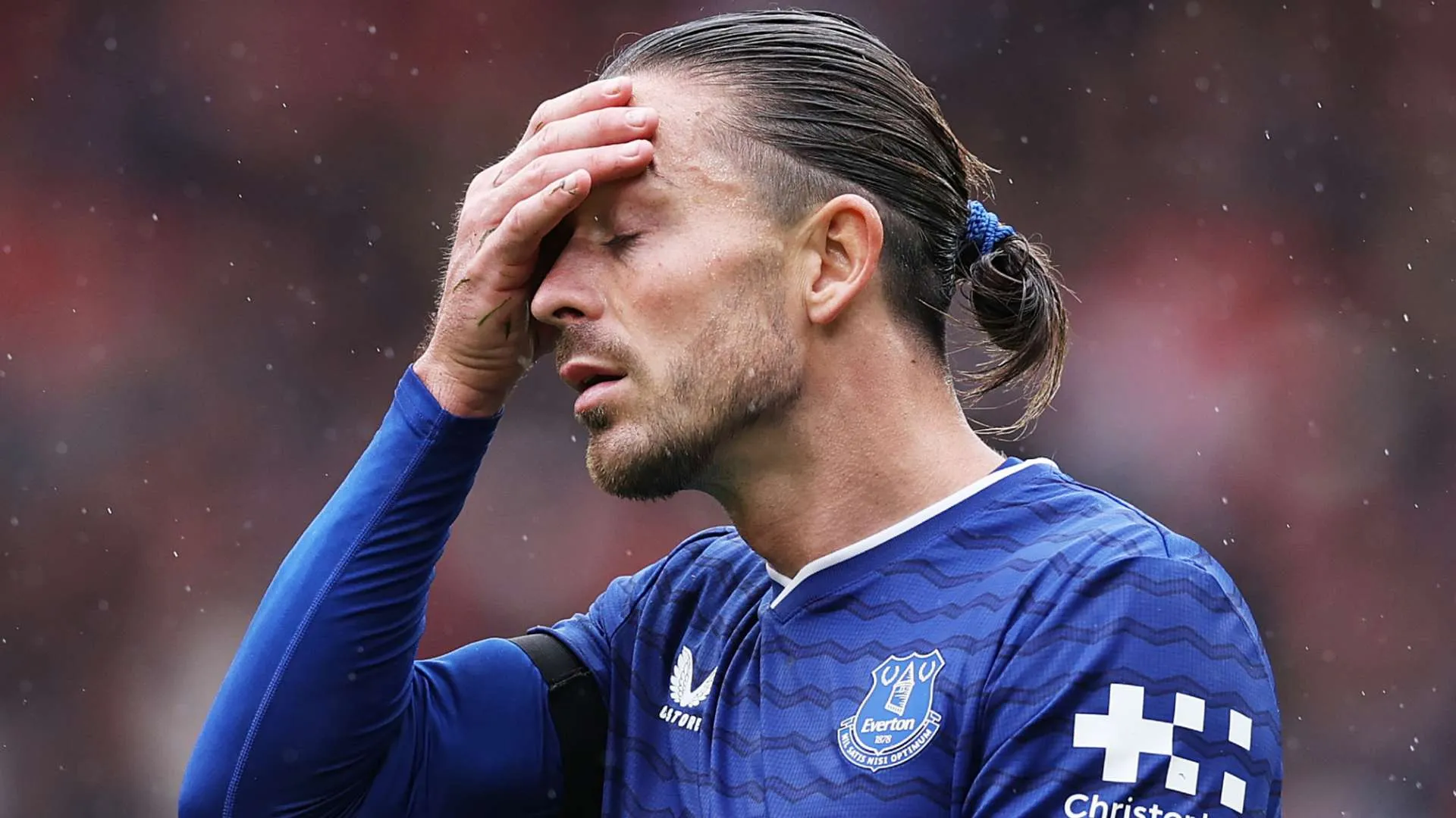 لاعب كرة القدم جاك غريليش يرتدي زي إيفرتون ويضع يده على وجهه بتعبير يظهر الألم أو الإحباط خلال مباراة بالدوري الإنجليزي الممتاز.