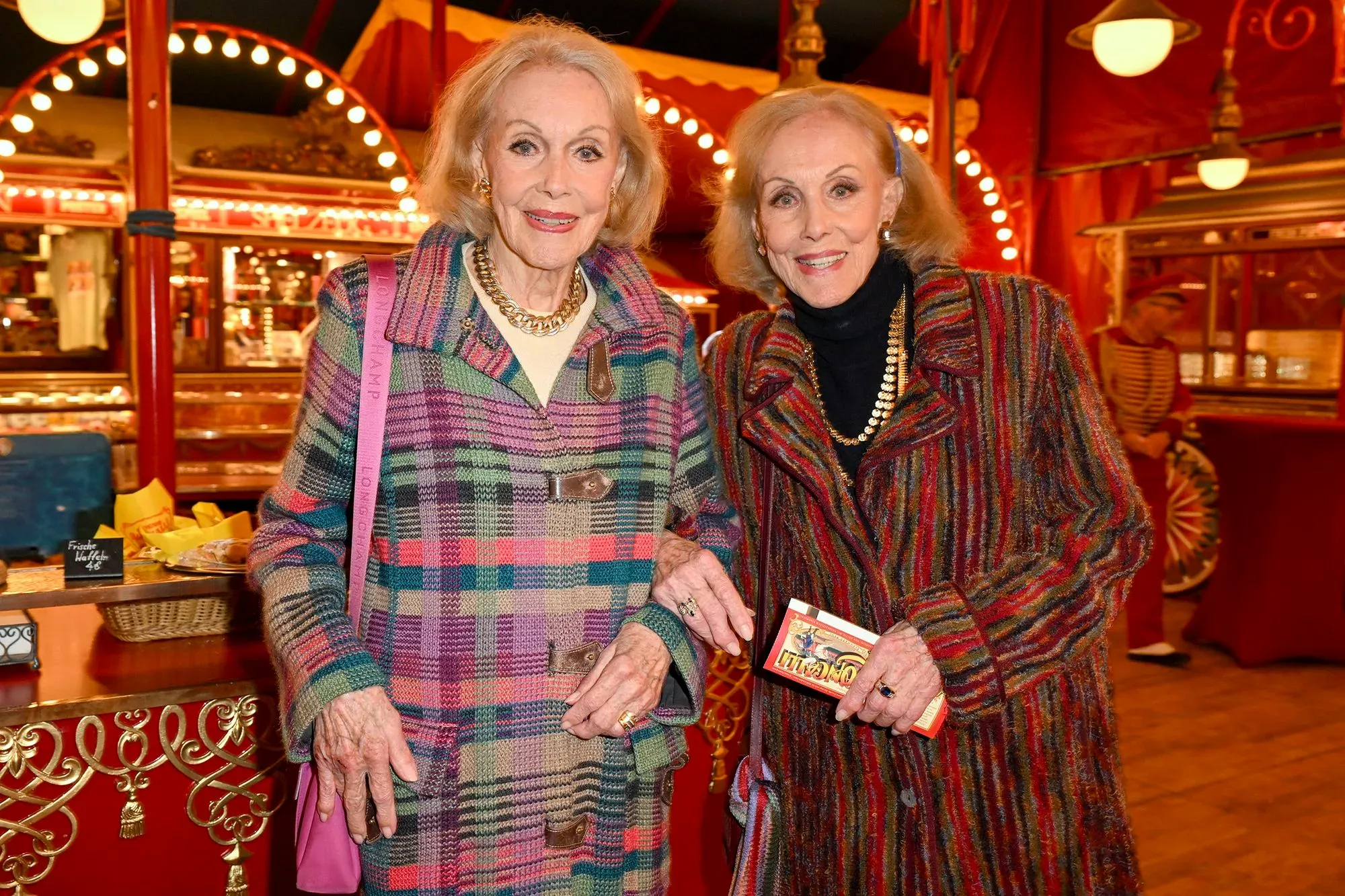 تظهر أليس وإلين كيسلر، التوأم الألماني الشهير، بابتسامات وهما ترتديان معاطف ملونة في حدث عام، يعكسان سحرهما كفنانتين في الخمسينيات.