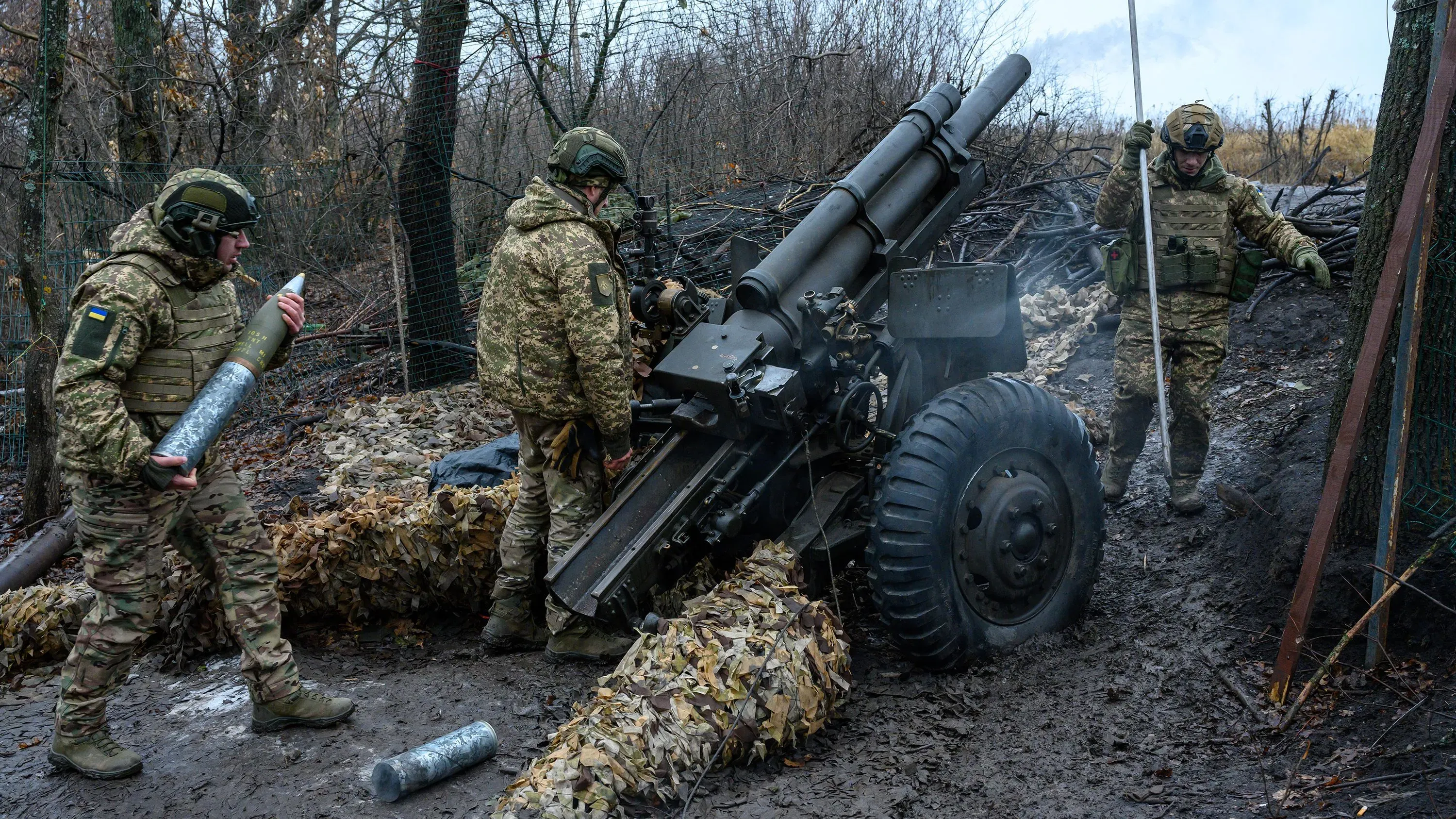 جنود أوكرانيون يعملون على تجهيز مدفع ميداني في منطقة عسكرية، مع التركيز على أهمية زيادة الإنفاق الدفاعي في أوروبا.