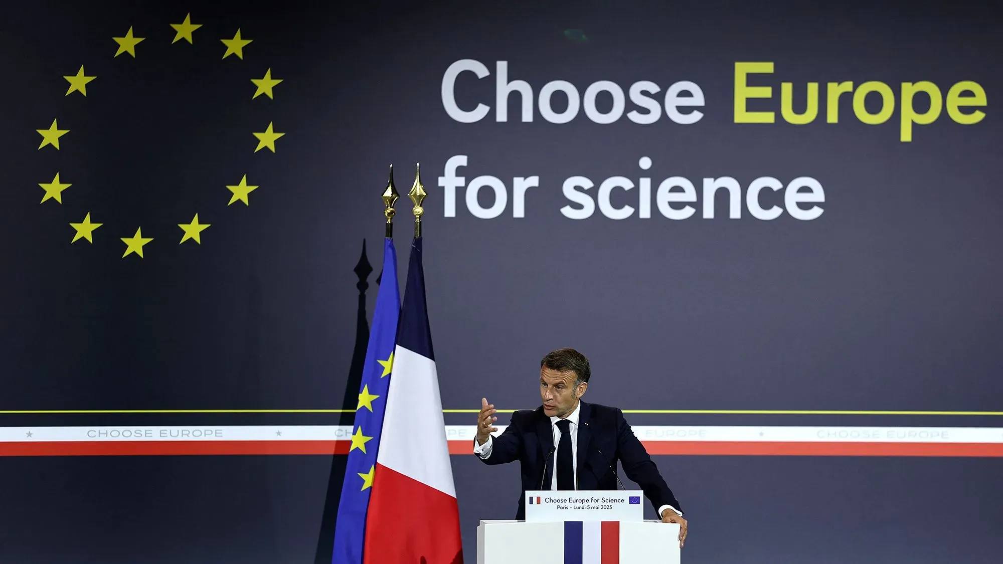 ماكرون يتحدث في فعالية "اختر أوروبا من أجل العلم" بجامعة السوربون، مع العلم الفرنسي والأوروبي خلفه، مؤكدًا أهمية دعم البحث العلمي.