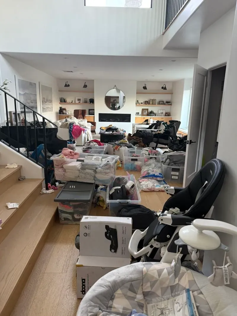 غرفة معيشة مزدحمة بأكياس ملابس وألعاب وأغراض للأطفال، تعكس جهود السكان لدعم المتضررين من حرائق لوس أنجلوس.