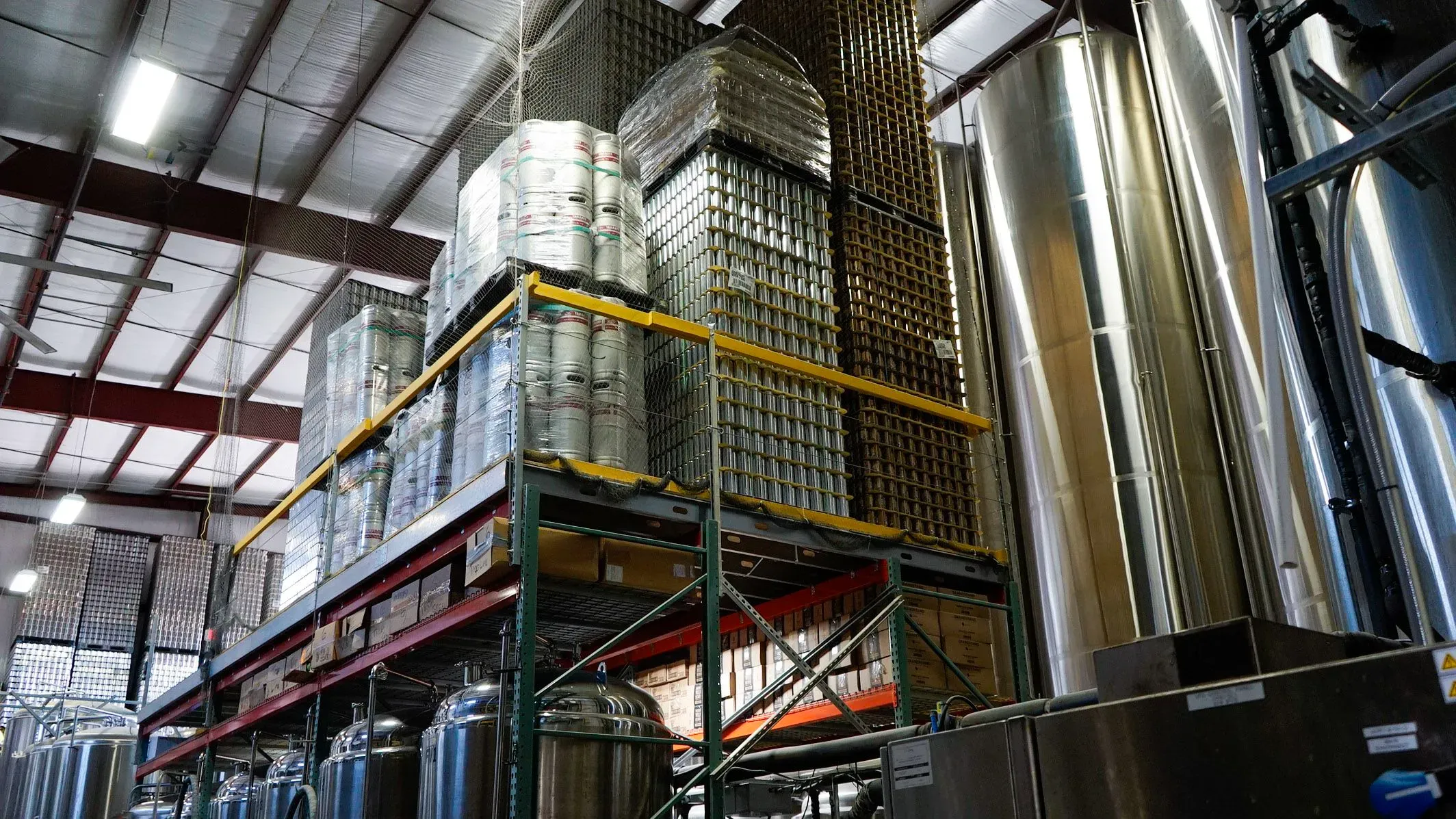 مستودع مصنع البيرة TailGate في ناشفيل، يظهر فيه حاويات الألمنيوم المعبأة والبراميل، يعكس تأثير التعريفات الجمركية على الصناعة.