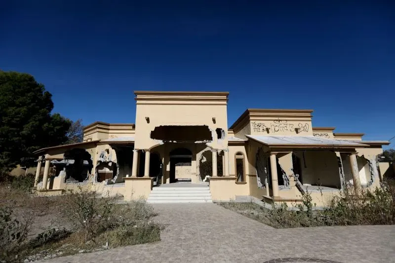 منزل مهجور في منطقة كولومبية، يظهر آثار التدمير والكتابات على الجدران، مما يعكس تأثيرات العنف المرتبط بحروب المخدرات.