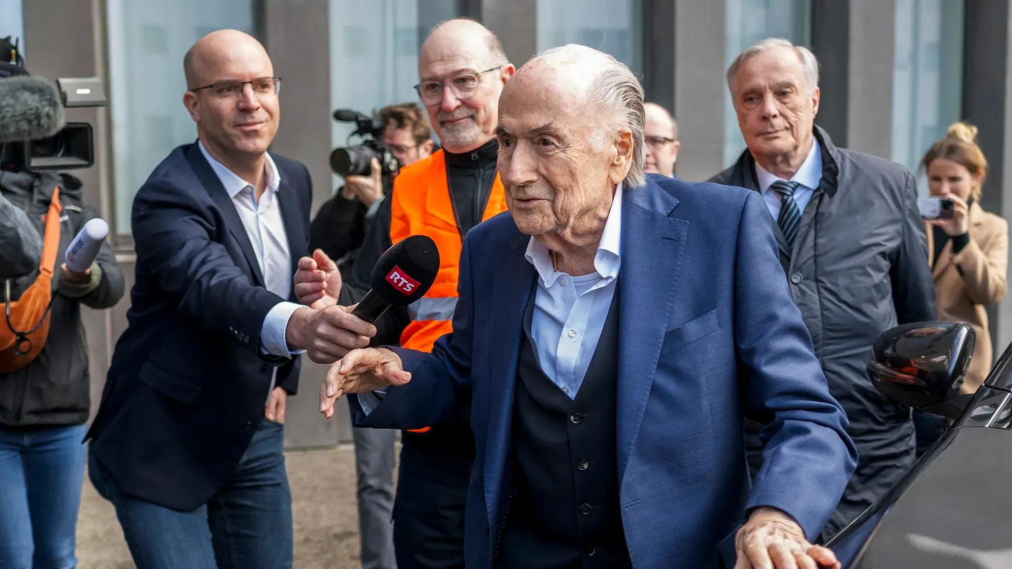 رئيس الفيفا السابق سيب بلاتر يغادر المحكمة محاطًا بالصحفيين، بعد تبرئته من تهم الفساد المتعلقة بمبلغ 2.26 مليون دولار.