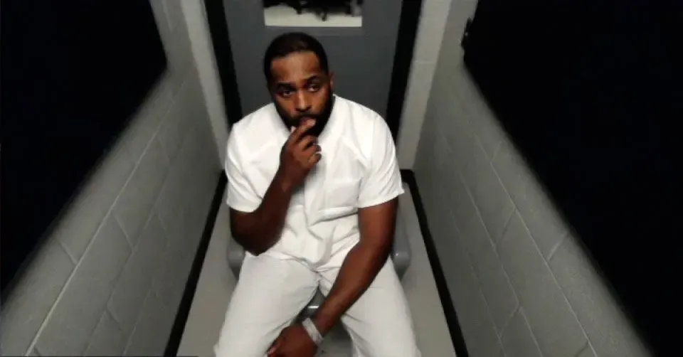 مدرب كرة القدم المُقال شيرون مور يجلس في قاعة المحكمة مرتديًا ملابس السجن البيضاء، معبرًا عن حالة من التوتر بعد اتهامه بارتكاب جنح وجنايات.