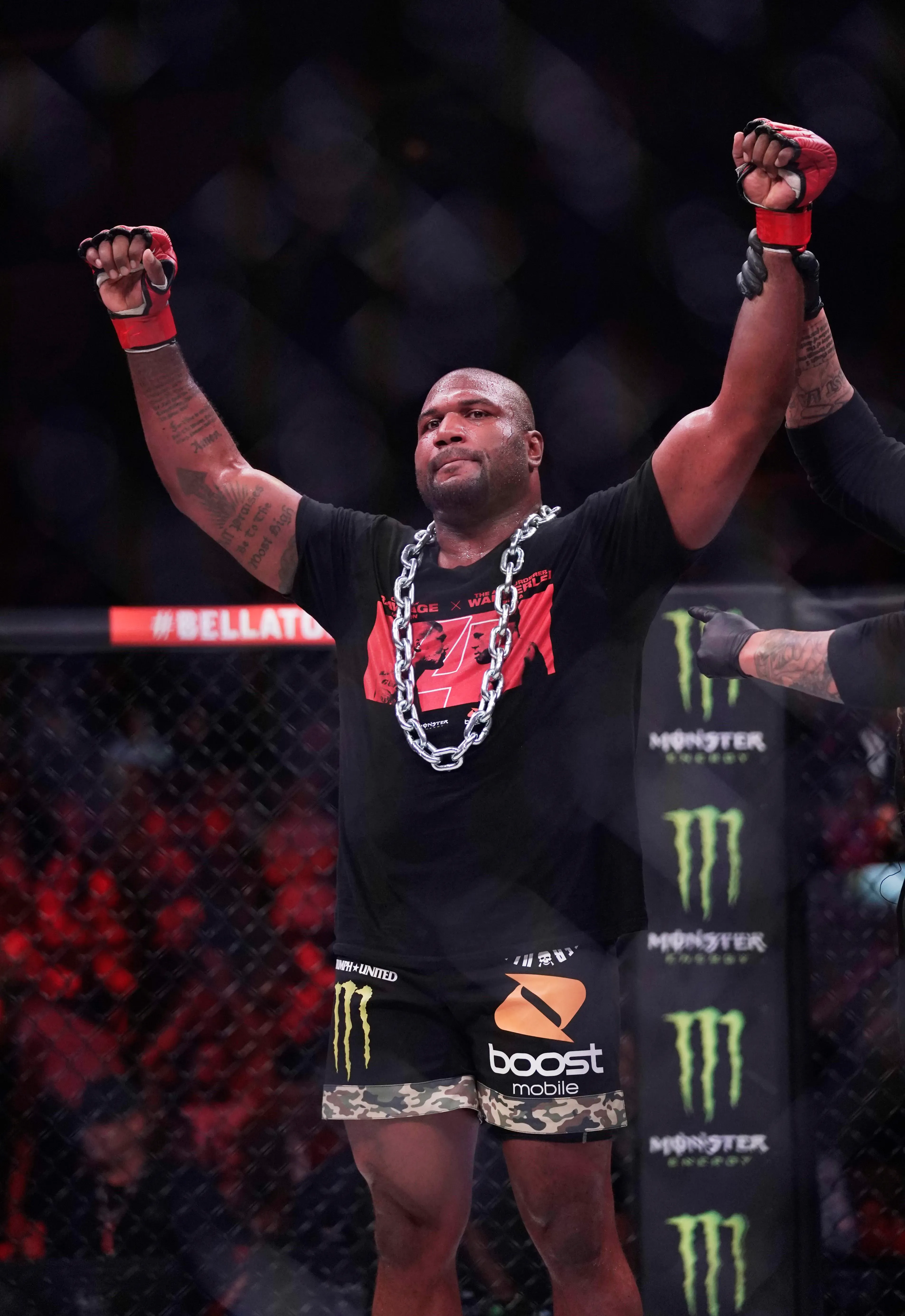 راجا جاكسون، مقاتل فنون القتال المختلطة، يرفع يديه في علامة الانتصار بعد نزال، وسط حلبة مليئة بالمعجبين.