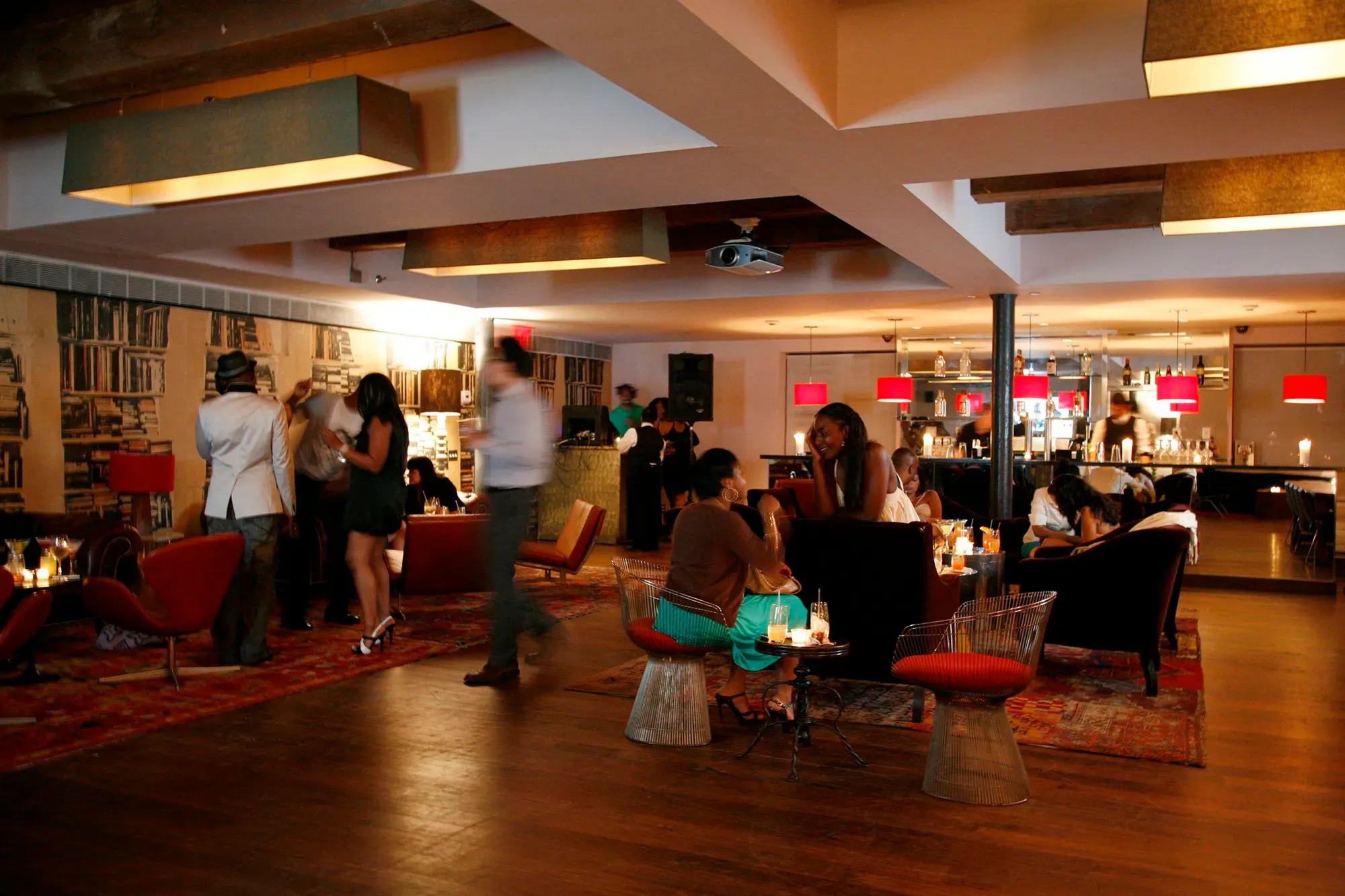 تصميم داخلي أنيق لمطعم سوهو هاوس، يظهر الزبائن يستمتعون بأجواء حيوية مع أضواء دافئة وديكور عصري، يعكس روح الإبداع والرفاهية.