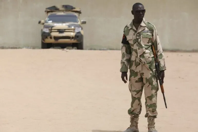 جندي نيجيري يرتدي زيًا عسكريًا ويحمل سلاحًا، يقف في موقع بالقرب من مسجد في مايدوجوري بعد الانفجار الذي وقع أثناء صلاة العشاء.