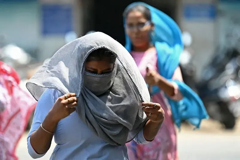 نساء يرتدين ملابس واقية من الشمس في يوم حار، يعكس تأثير موجات الحر المتزايدة في الهند وباكستان على الحياة اليومية.