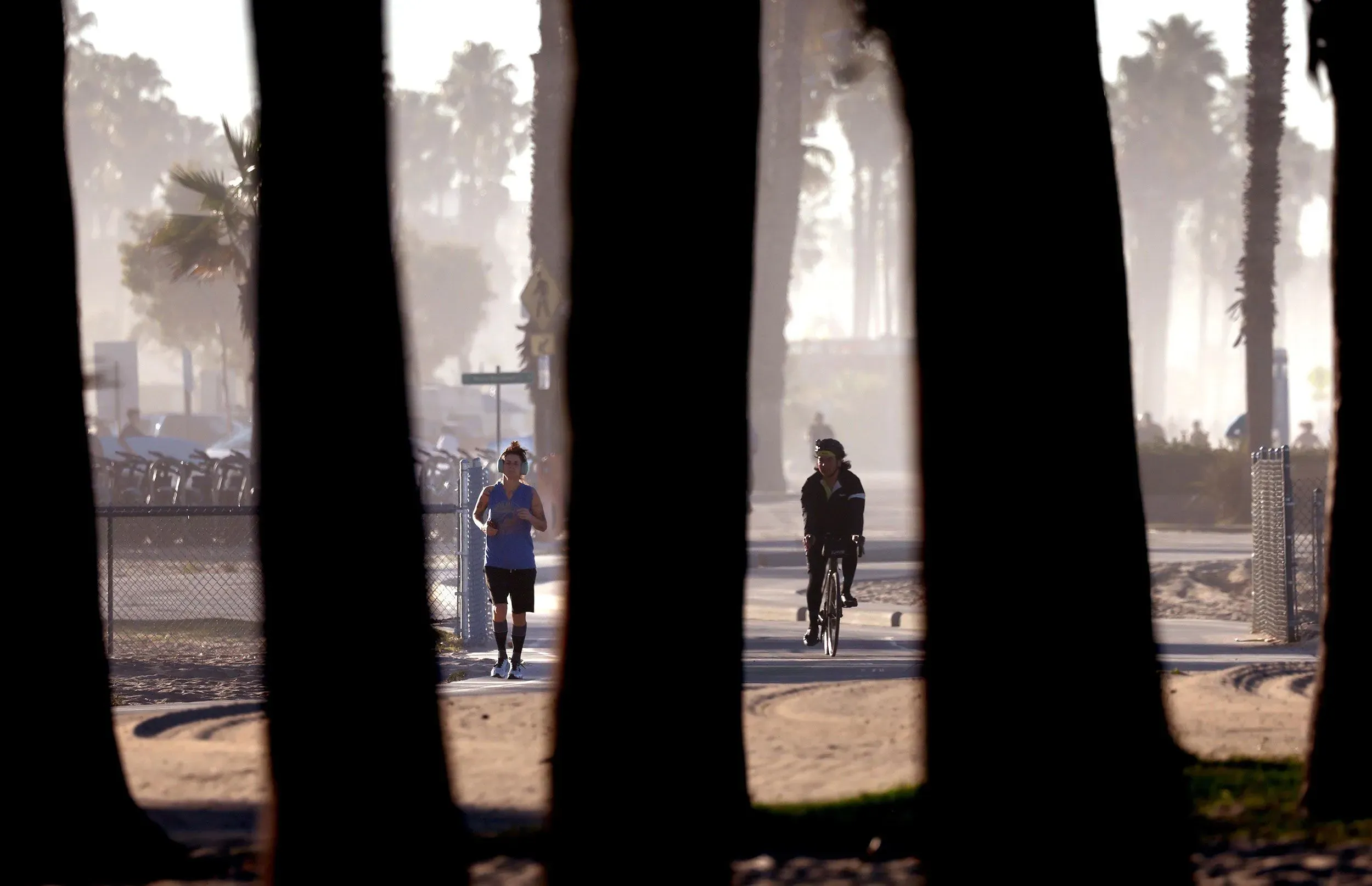 صورة لراكض وراكب دراجة في حديقة تحت أشعة الشمس الساطعة، مع تلميحات لموجة حر قادمة تؤثر على المناطق الغربية من الولايات المتحدة.