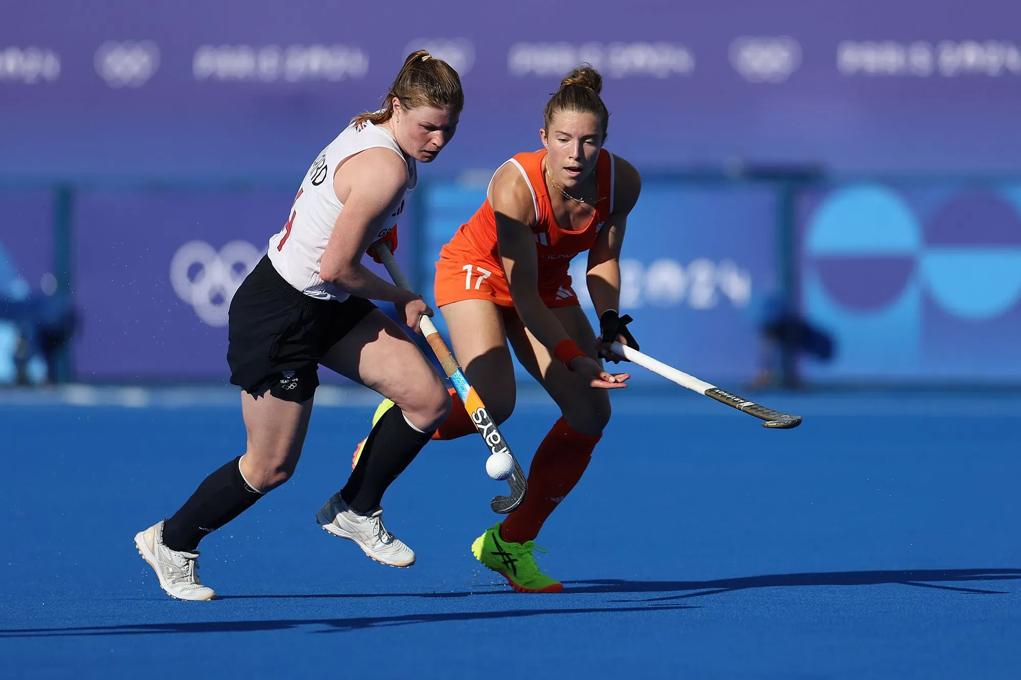 لاعبة هوكي ميداني تتنافس في مباراة أولمبية، ترتدي زيًا رياضيًا ضيقًا، مما يؤثر على أدائها وثقتها.