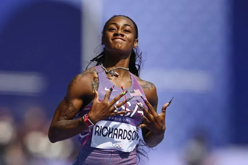 عداءة تظهر بفخر أثناء سباق، مع أظافر مصممة بشكل مزخرف، تعكس أسلوبها الشخصي وثقتها قبل المنافسة.