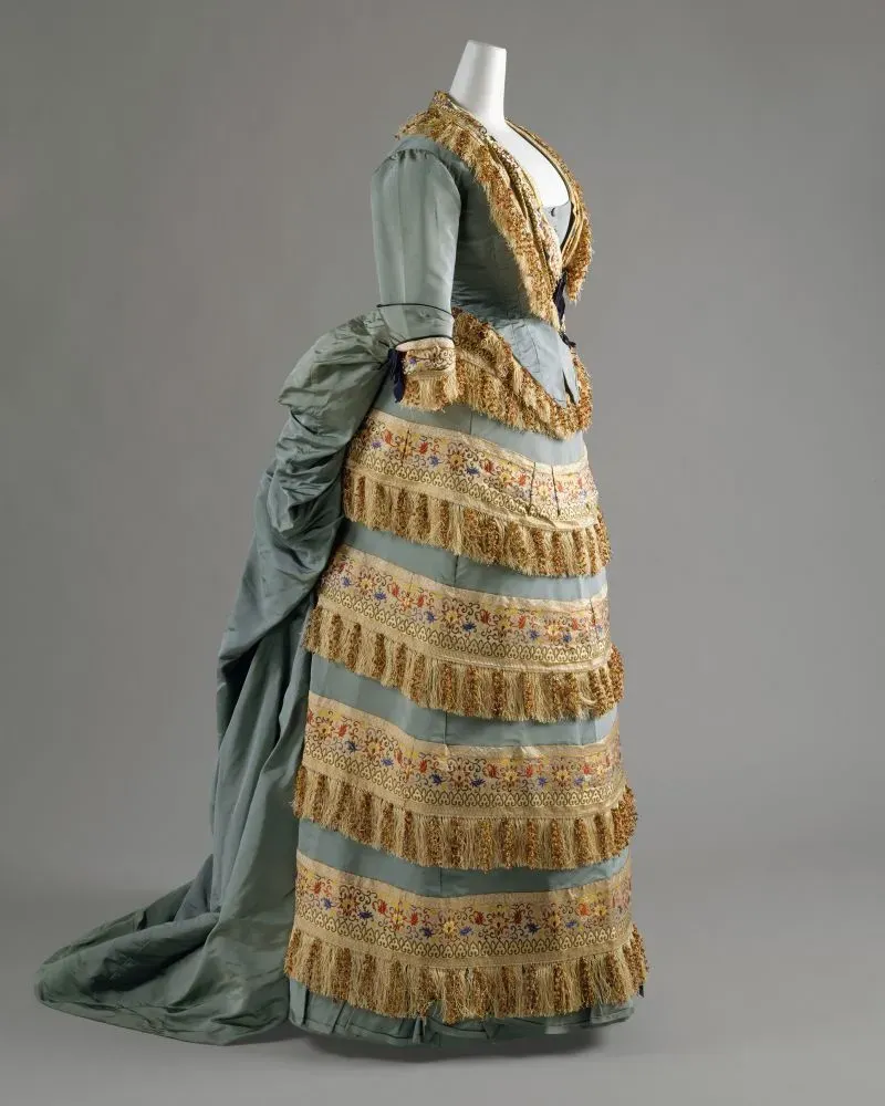 فستان تاريخي من تصميم تشارلز فريدريك وورث، يظهر تفاصيل الزخرفة والتصميم الفاخر الذي يعكس أسلوب الأزياء الراقية في القرن التاسع عشر.