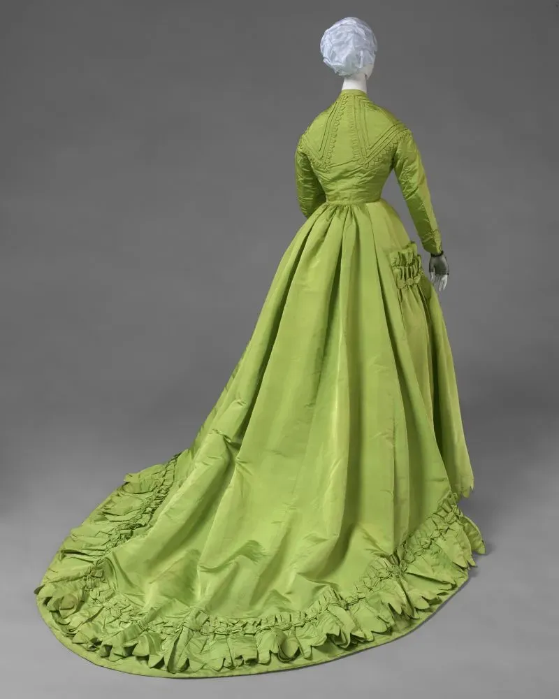 فستان طويل بلون أخضر فاتح من تصميم تشارلز فريدريك وورث، يظهر تفاصيله الدقيقة وقصته الفريدة في معرض "وورث: اختراع الأزياء الراقية" في باريس.