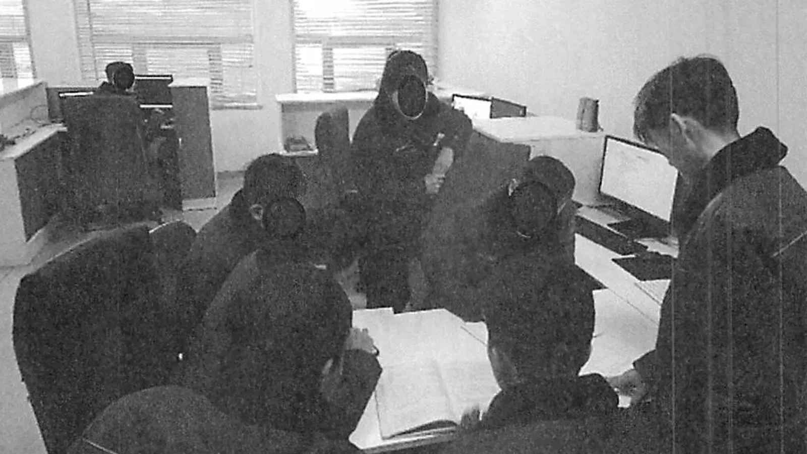 مجموعة من الأشخاص يعملون في مكتب، مع أجهزة كمبيوتر محمولة على الطاولات، في سياق جهود كوريا الشمالية لاستخدام التكنولوجيا عن بعد لتمويل برامجها.