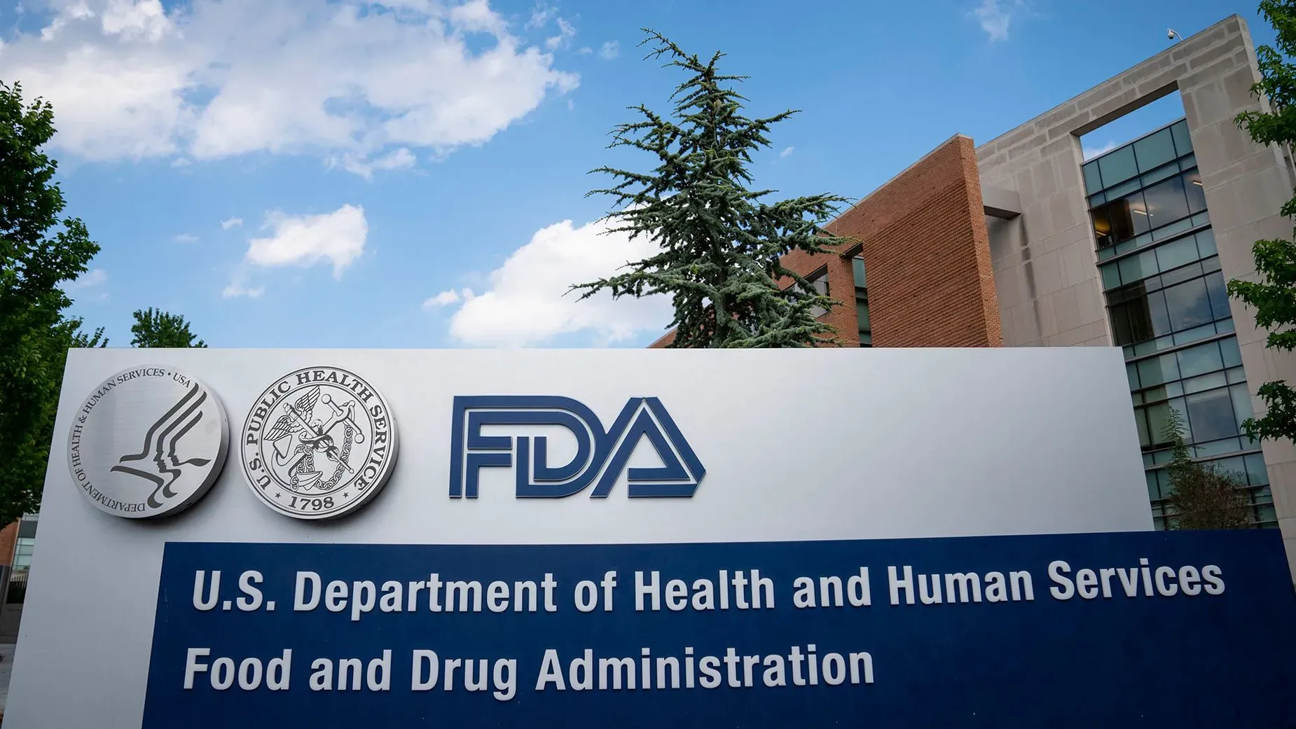 لافتة تحمل شعار إدارة الغذاء والدواء الأمريكية (FDA) مع مبنى خلفي، تشير إلى الموافقة على مضاد حيوي جديد لعلاج التهابات المسالك البولية.