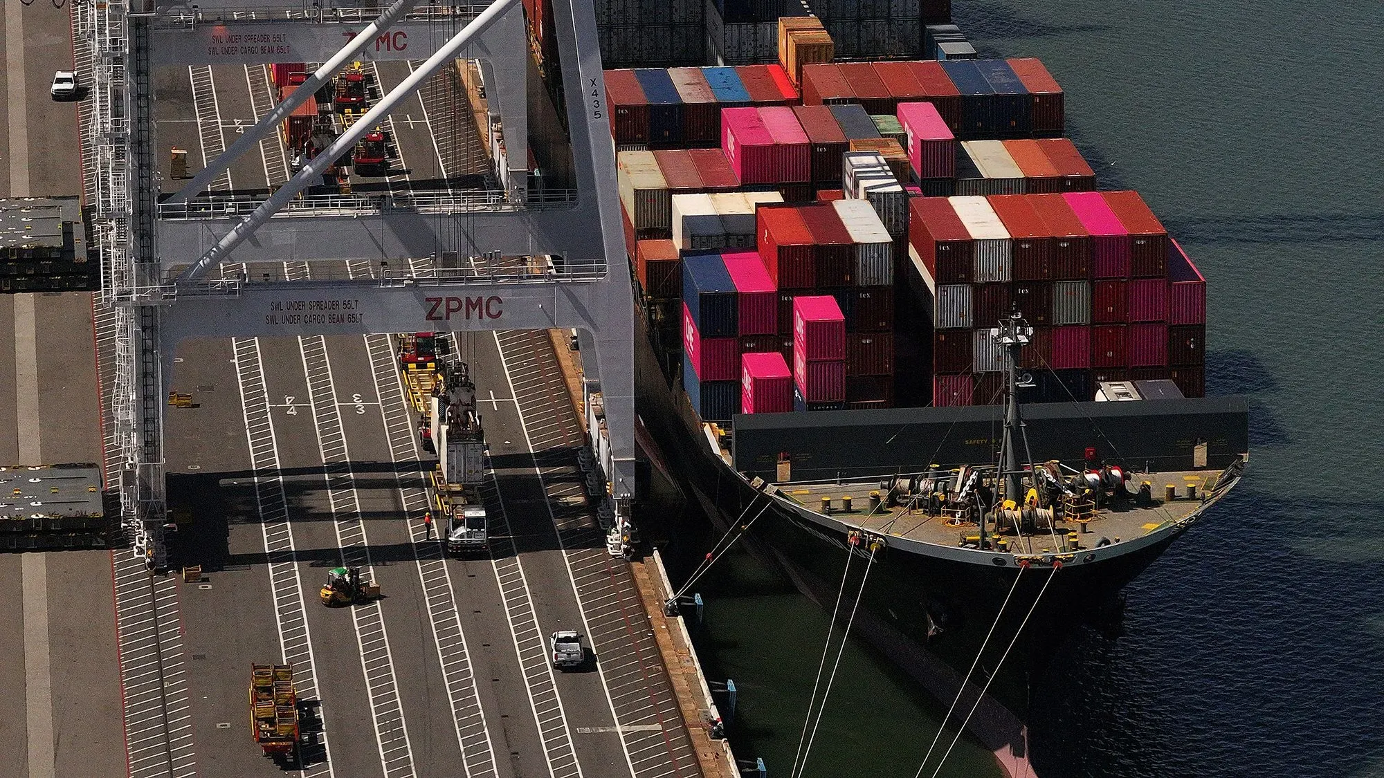 سفينة شحن محملة بالحاويات الملونة في ميناء، تعكس تأثيرات الحرب التجارية على الاقتصاد الأمريكي وسوق العمل.