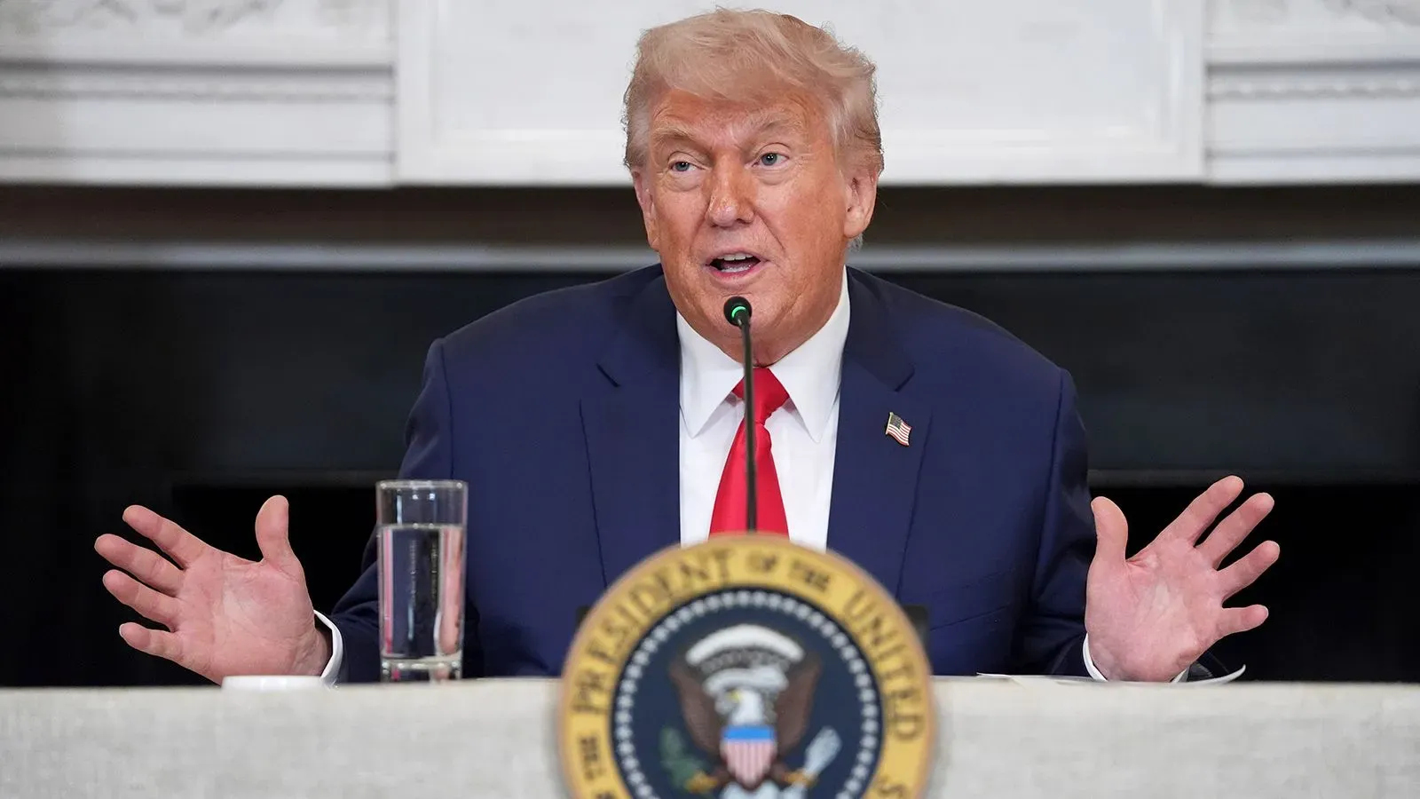 ترامب يتحدث في مؤتمر صحفي، معبرًا عن موقفه بشأن قضيته القانونية المتعلقة بأموال الرشوة، مع وجود شعار الرئاسة خلفه.