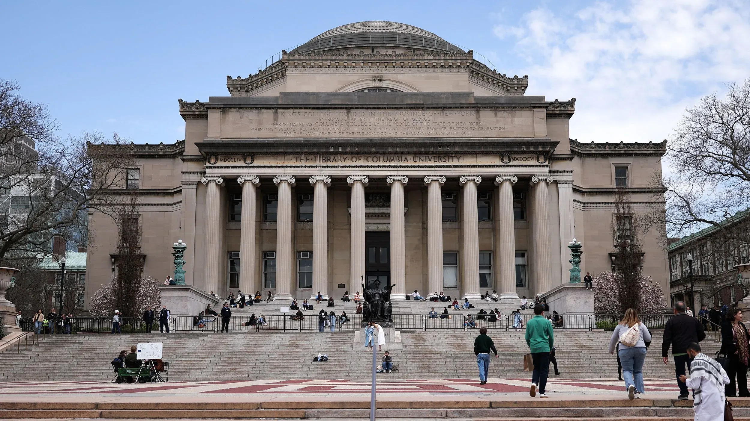 واجهة مكتبة جامعة كولومبيا، حيث يتجمع الطلاب على الدرج. تعكس الصورة أهمية التعليم العالي للطلاب الدوليين في ظل التحديات القانونية.