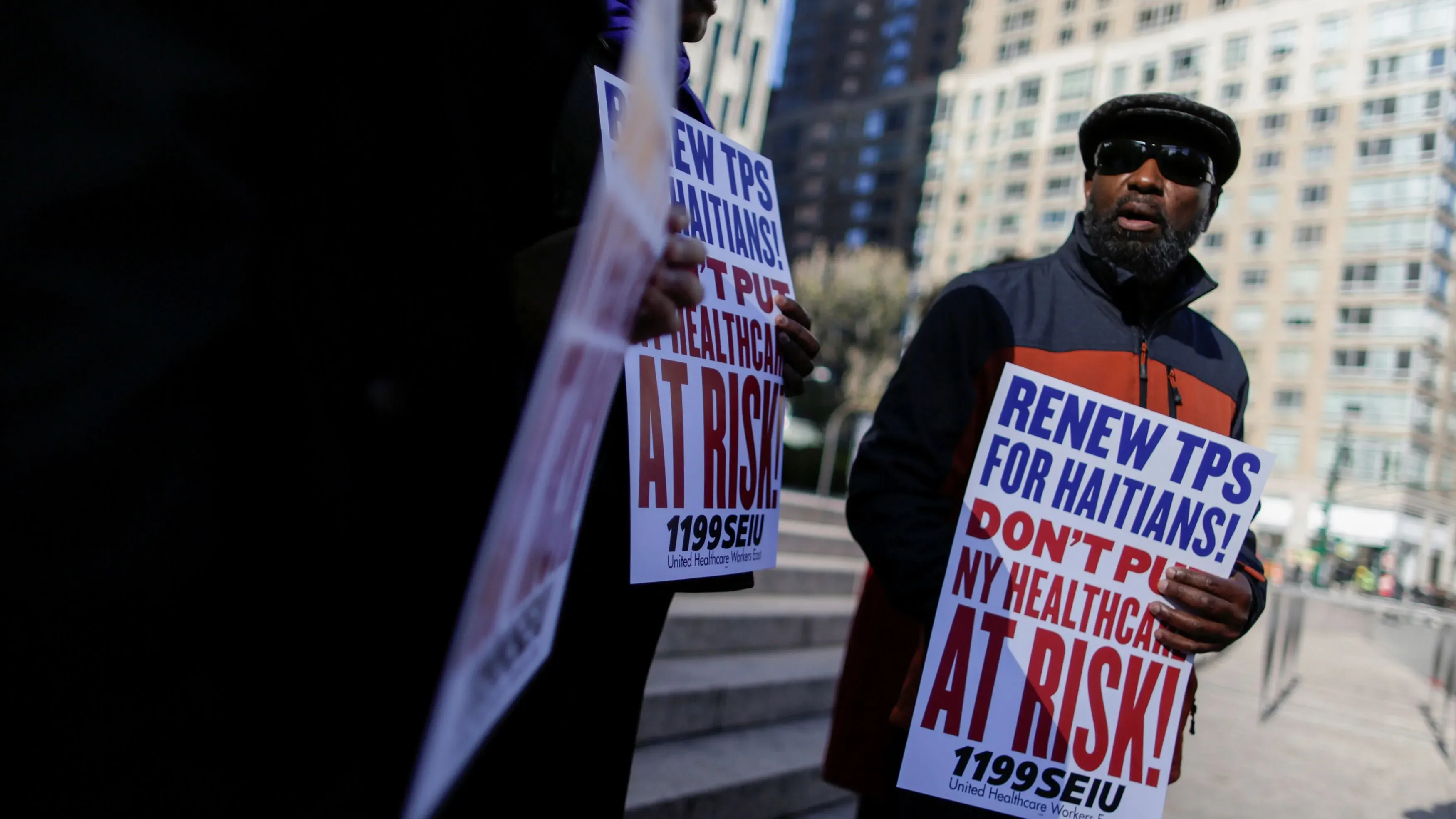 رجل يحمل لافتة تطالب بتجديد وضع الحماية المؤقتة للهايتيين، يظهر في تظاهرة للدفاع عن حقوق المهاجرين في نيويورك.