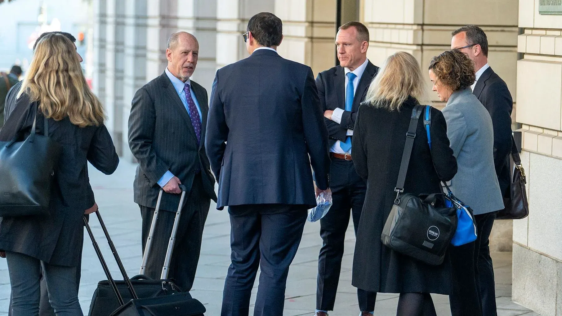 مجموعة من الأشخاص يتحدثون أمام مبنى حكومي، يتضمن محاميين وصحفيين، في سياق حكم قضائي يتعلق بوصول وكالة أسوشييتد برس.