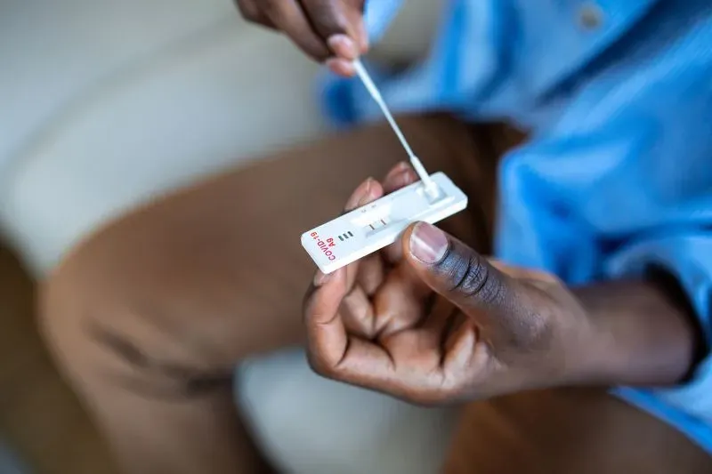 رجل يستخدم اختبار منزلي للكشف عن فيروس كوفيد-19، مشيراً إلى أهمية الفحص للأعراض الحادة والوقاية في فصل الشتاء.