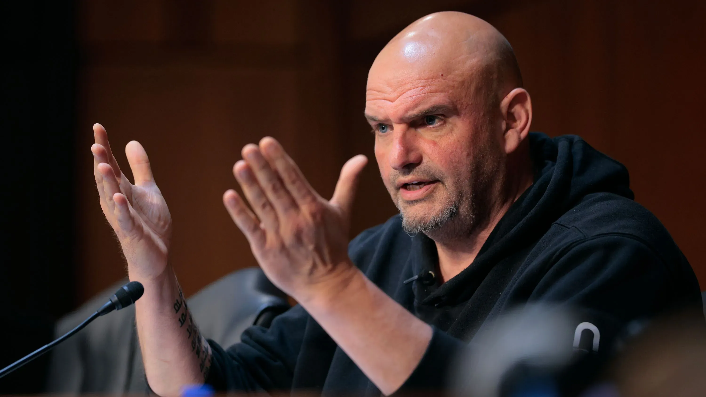 النائب جون فيترمان يتحدث بحماس أثناء جلسة استماع، معبراً عن آرائه حول موضوعات سياسية هامة.