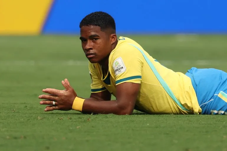 لاعب كرة قدم برازيلي يرتدي زي المنتخب الأصفر مستلقٍ على أرض الملعب خلال مباراة كأس العالم، يعكس لحظة من التوتر والإحباط.