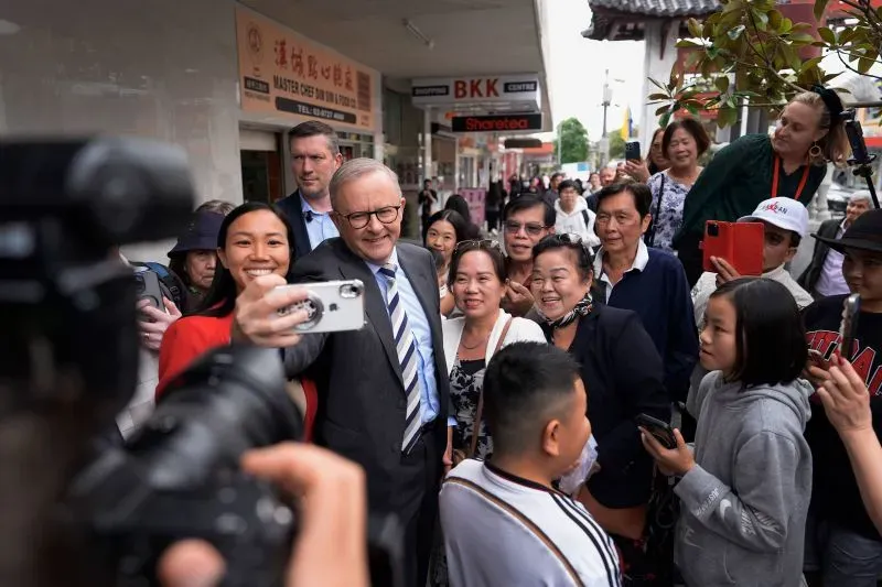 أنتوني ألبانيز، زعيم حزب العمال الأسترالي، يتفاعل مع مجموعة من الناخبين خلال حملة انتخابية، مع وجود حشود خلفه.