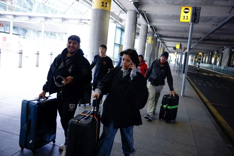 ركاب يسيرون في مطار هيثرو، يحملون حقائبهم، وسط أجواء من الازدحام والاضطراب بعد إغلاق المطار بسبب حريق.