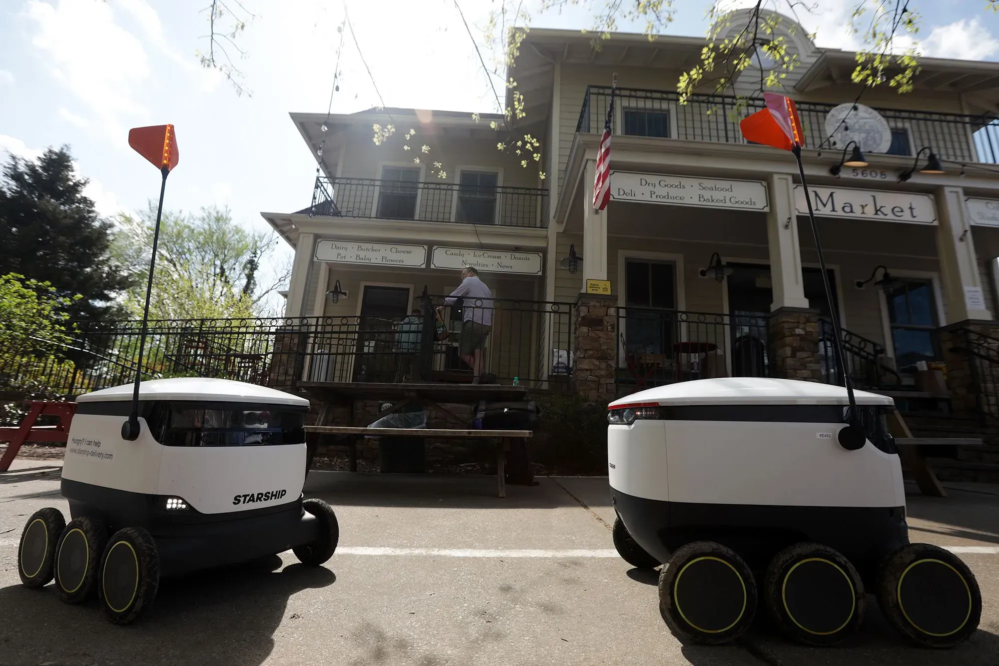 روبوتات توصيل الطعام "كورتني" و"ستار شيب" أمام مطعم، تحمل طلبات أوبر إيتس، تعكس تزايد استخدام التكنولوجيا في الحياة اليومية.