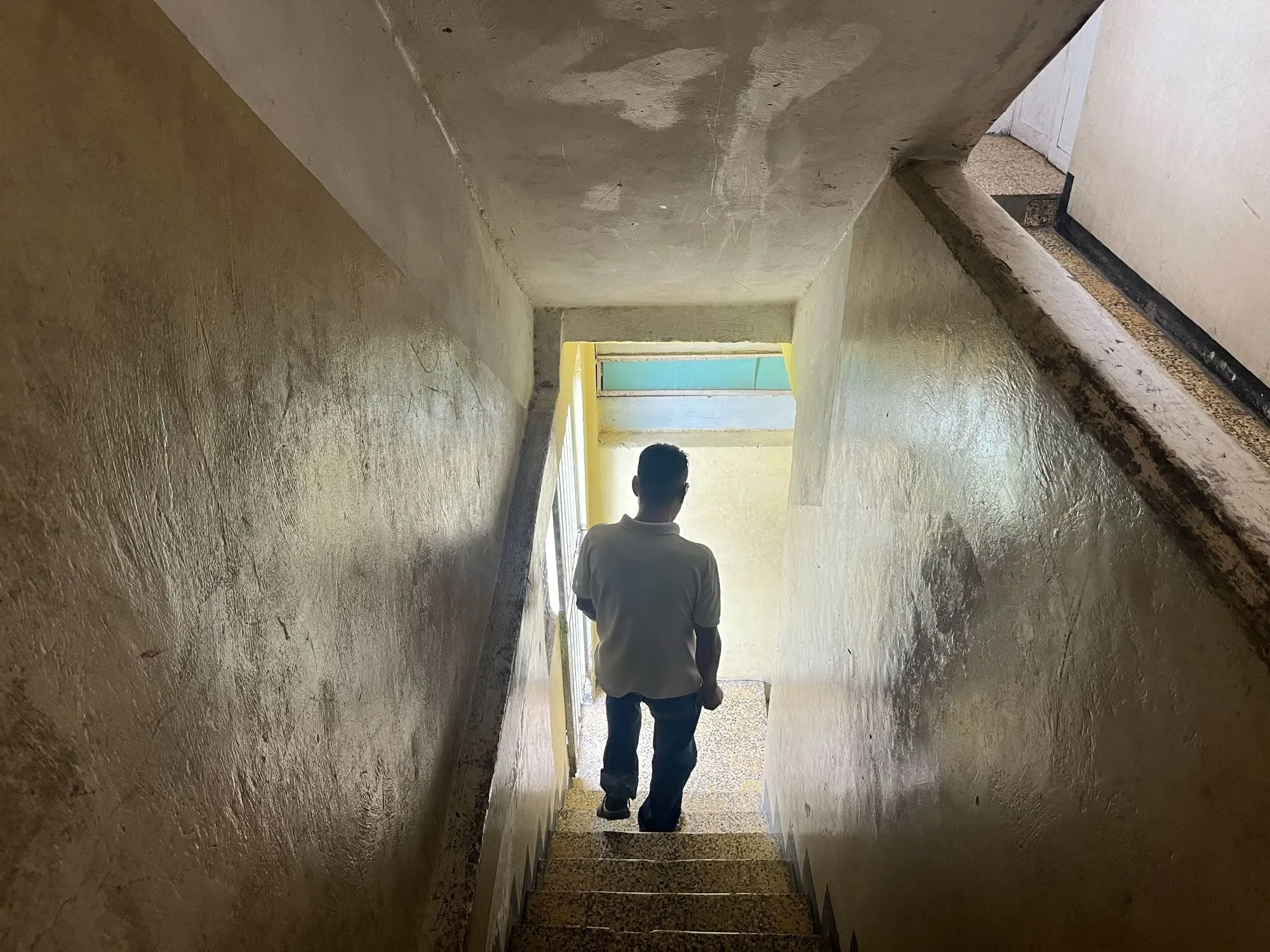 رجل يتجه نحو أسفل الدرج في منزل بسيط، يعكس التحديات اليومية التي يواجهها الفنزويليون في ظل الأزمات الاقتصادية والاجتماعية.