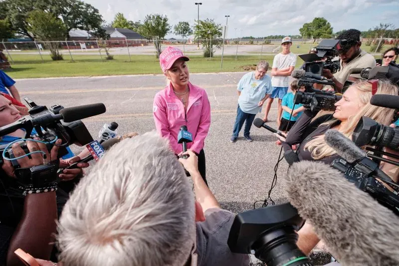 جولي كريسلي تتحدث إلى وسائل الإعلام خارج السجن، محاطة بمراسلين ومشجعين، تعبر عن دعمها وزوجها بعد الحكم عليهما.
