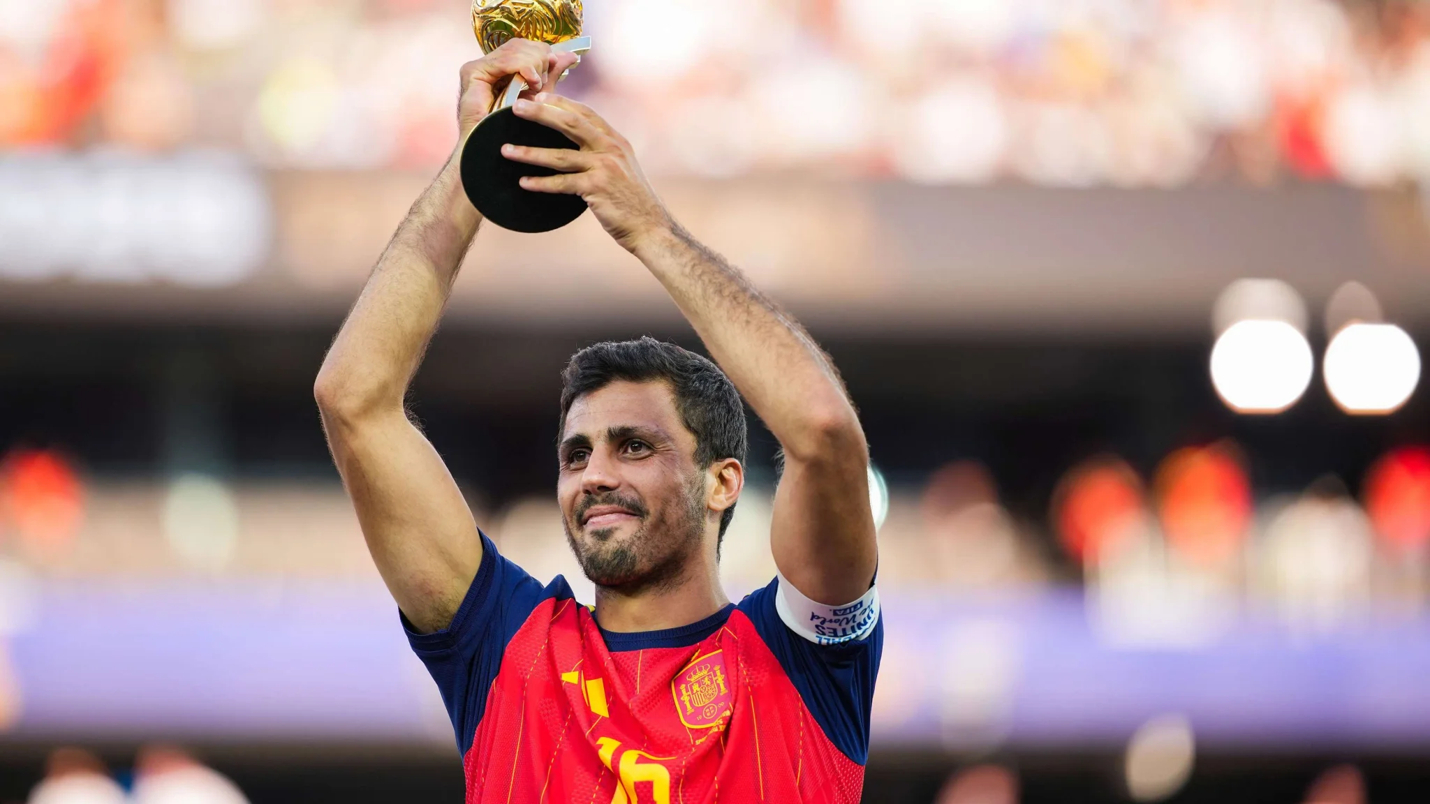 لاعب كرة قدم إسباني يرفع كأس العالم بفخر، مع التركيز على أهمية تعزيز خط وسط برشلونة في سوق الانتقالات الصيفية.