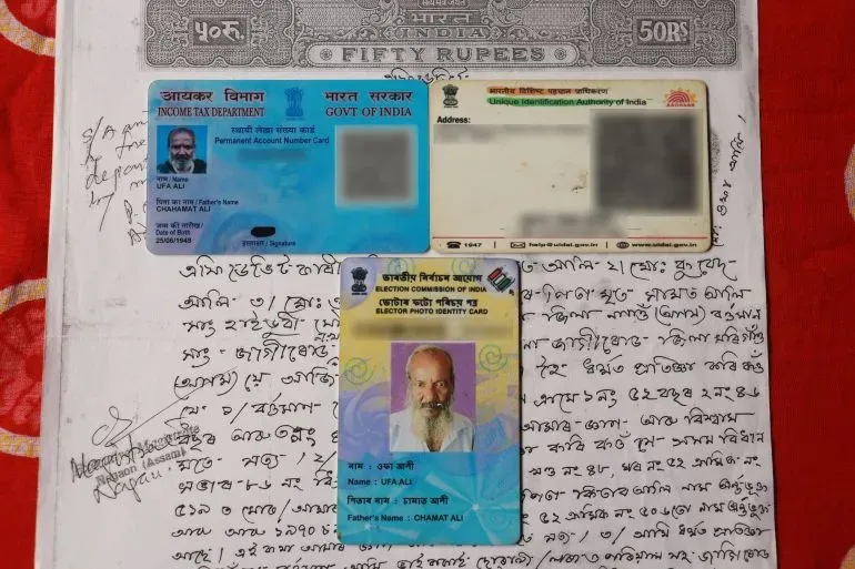 بطاقات هوية شخصية لمواطن هندي تُظهر تفاصيل مثل الاسم ورقم التعريف، موضوعة على ورقة مكتوبة بخط اليد، تعكس توترات الهوية في آسام.