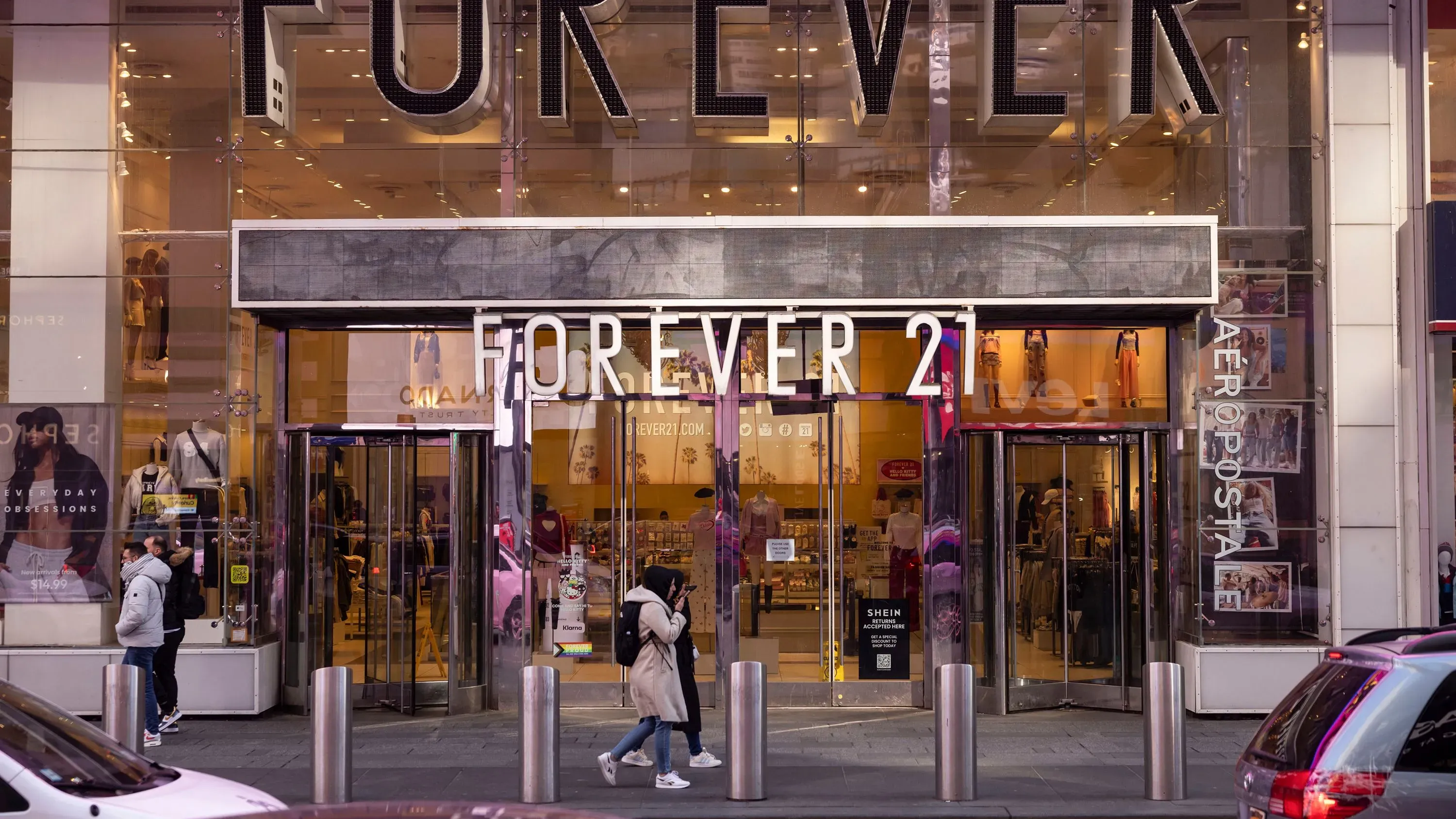 واجهة متجر Forever 21 في مدينة مزدحمة، مع زبائن يتجولون أمامه، تعكس التحديات التي تواجه العلامة التجارية في سوق الأزياء السريعة.