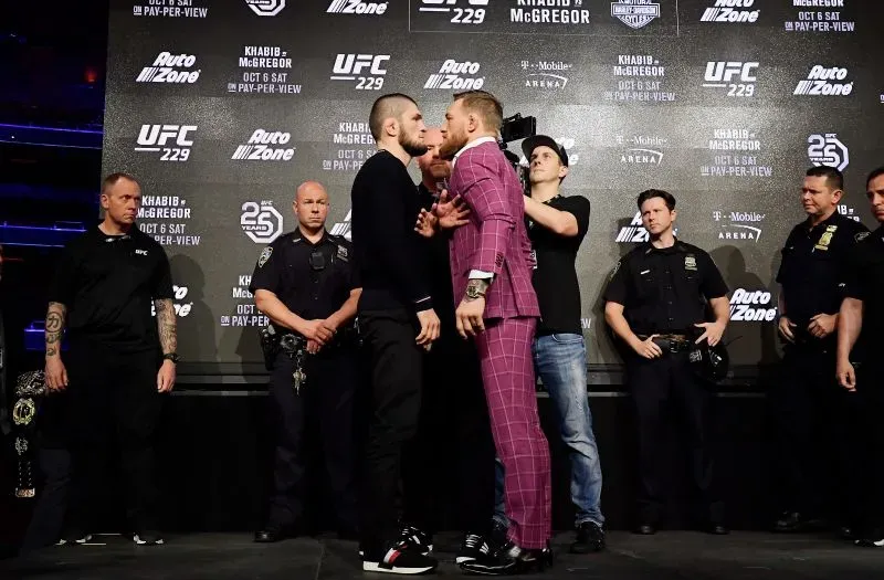 مواجهة مشحونة بين حبيب نورماغوميدوف وكونور مكجريجور في مؤتمر صحفي قبل نزال UFC 229، مع وجود رجال أمن في الخلفية.