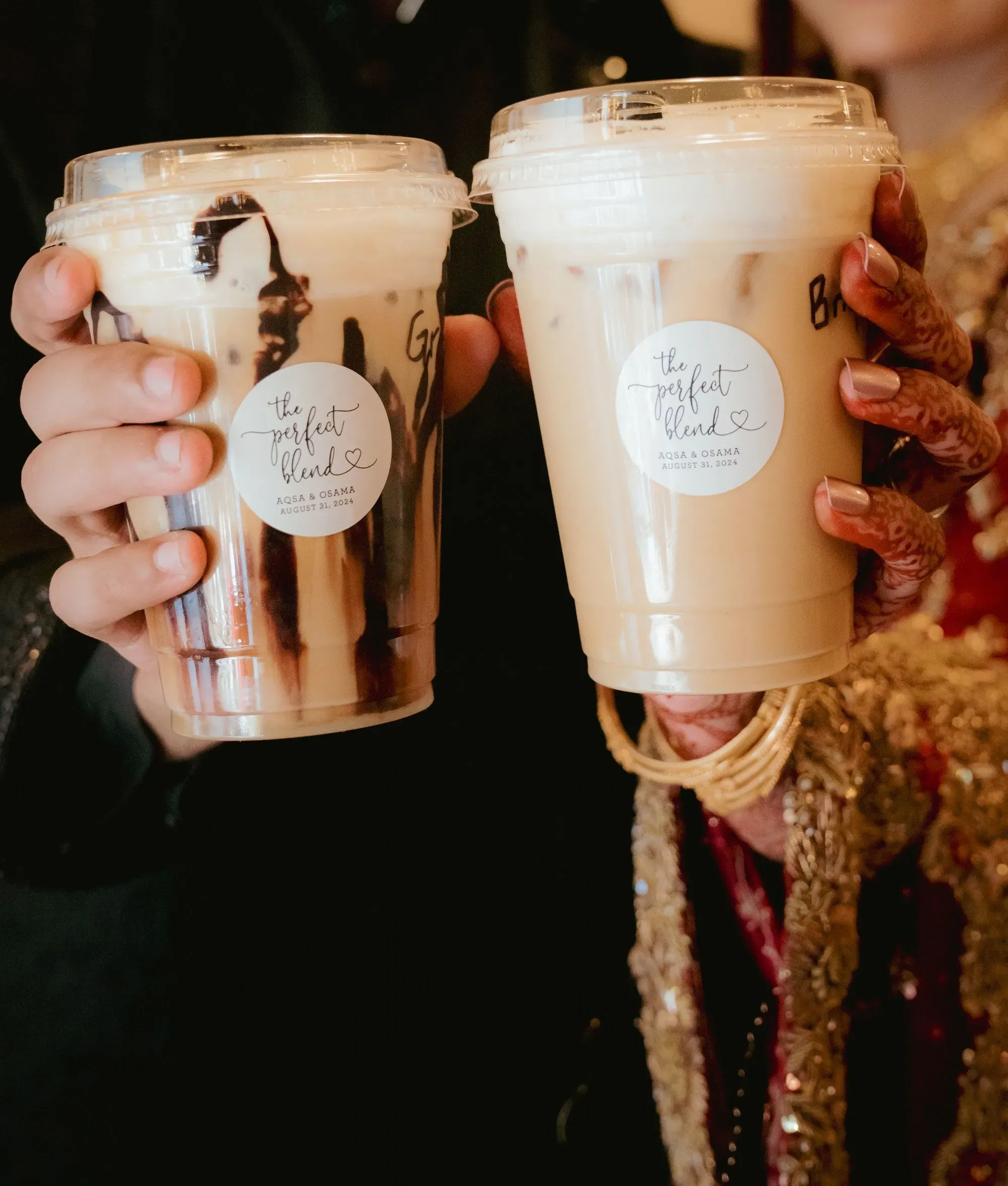 أكواب مشروبات مميزة تحمل علامة "المزج المثالي"، ممسكة بأيدٍ مزينة بالحناء، تعكس أجواء حفلات الزفاف في جنوب كاليفورنيا.