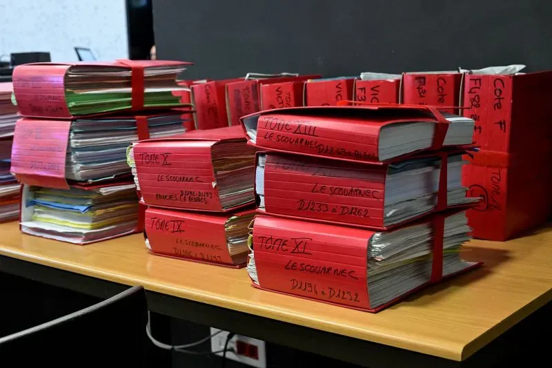 ملفات محكمة متراكمة باللون الأحمر، تحتوي على مستندات تتعلق بأكبر قضية اعتداء جنسي على الأطفال في فرنسا، مع 299 ضحية مزعومة.