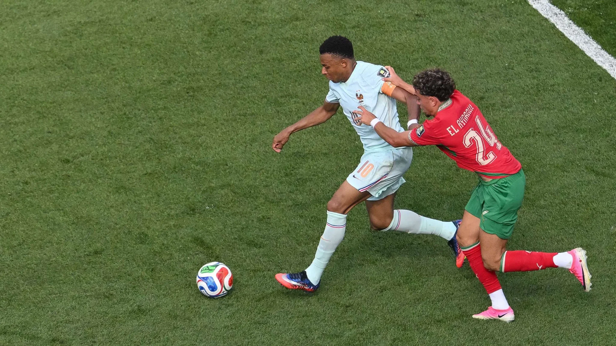 مباراة كرة قدم بين فرنسا والمغرب مع محاولة مراوغة من لاعب فرنسي وسط ضغط مدافع مغربي في كأس العالم.