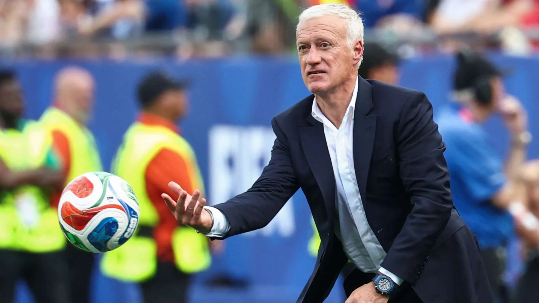 ديدييه ديشان مدرب منتخب فرنسا لكرة القدم يرمى الكرة خلال مباراة كأس العالم، مع تركيز واضح وأسلوب رسمي.
