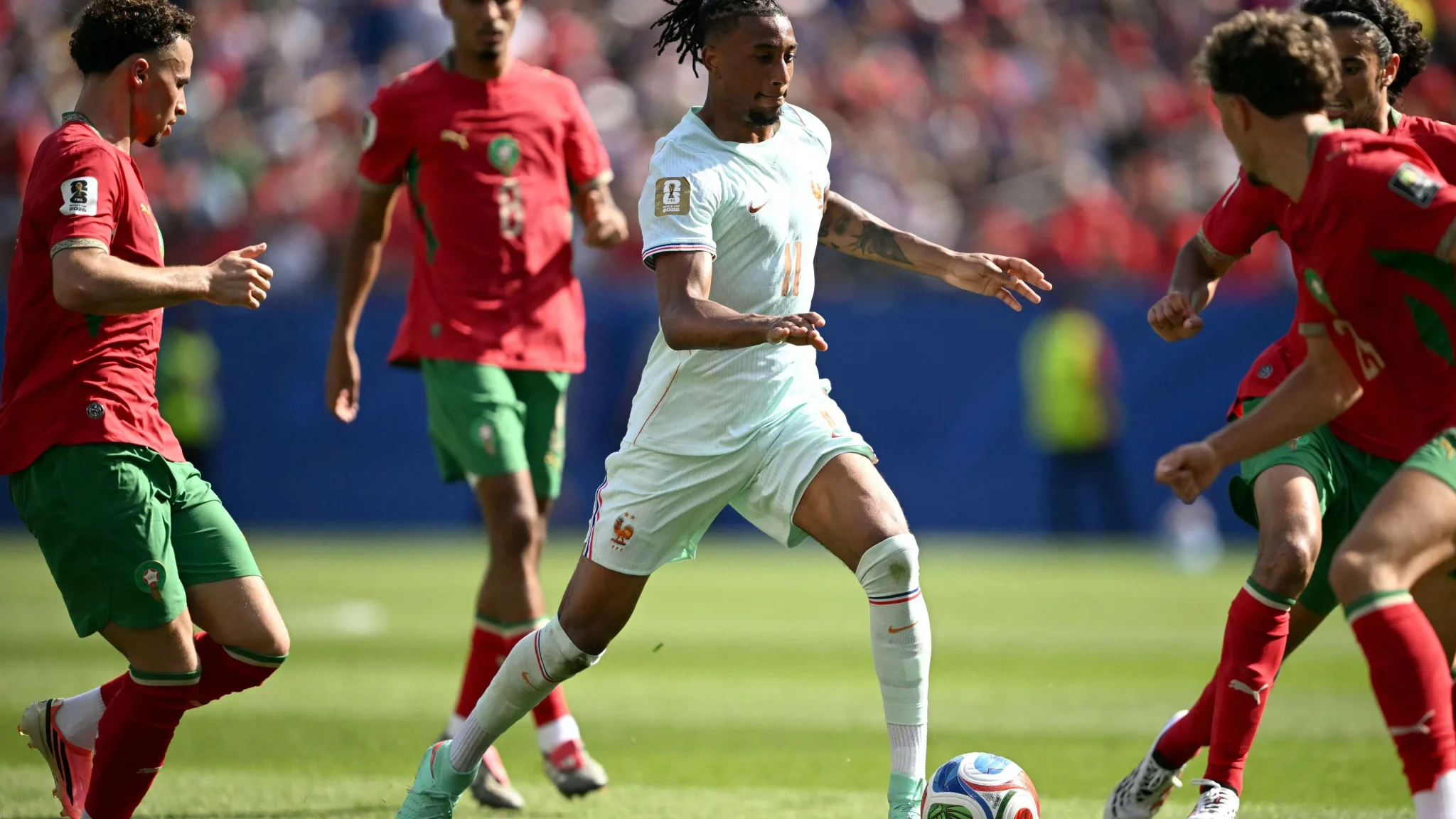 لاعب فرنسي يراوغ بين لاعبي منتخب المغرب خلال مباراة كأس العالم، في مشهد يعكس سيطرة فرنسا وهجومها المكثف.