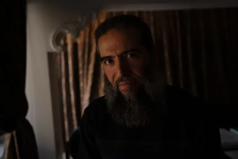 فؤاد نعال، رجل ذو لحية طويلة، يتحدث بحماس عن تجربته في السجون السورية تحت نظام الأسد، في شقته بدمشق.