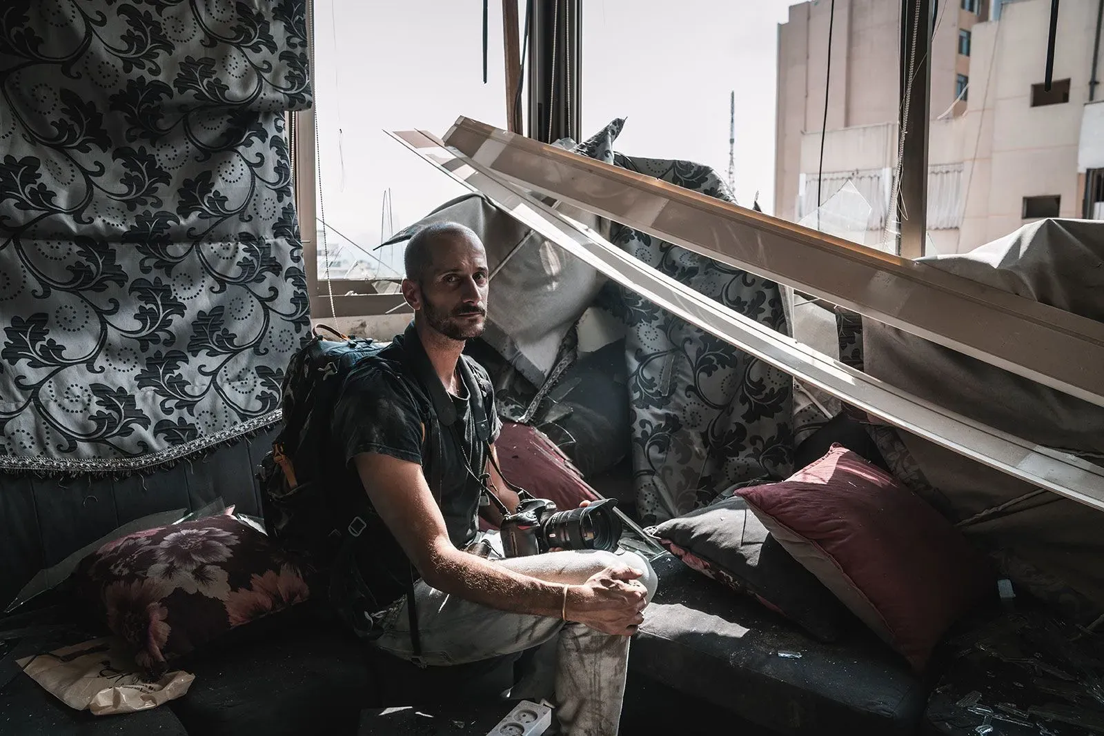 مصور صحفي يجلس في مكان دمرته الحرب، يحمل كاميرته، ويظهر عليه التعب والإجهاد في مواجهة الأوضاع الصعبة في أوكرانيا.