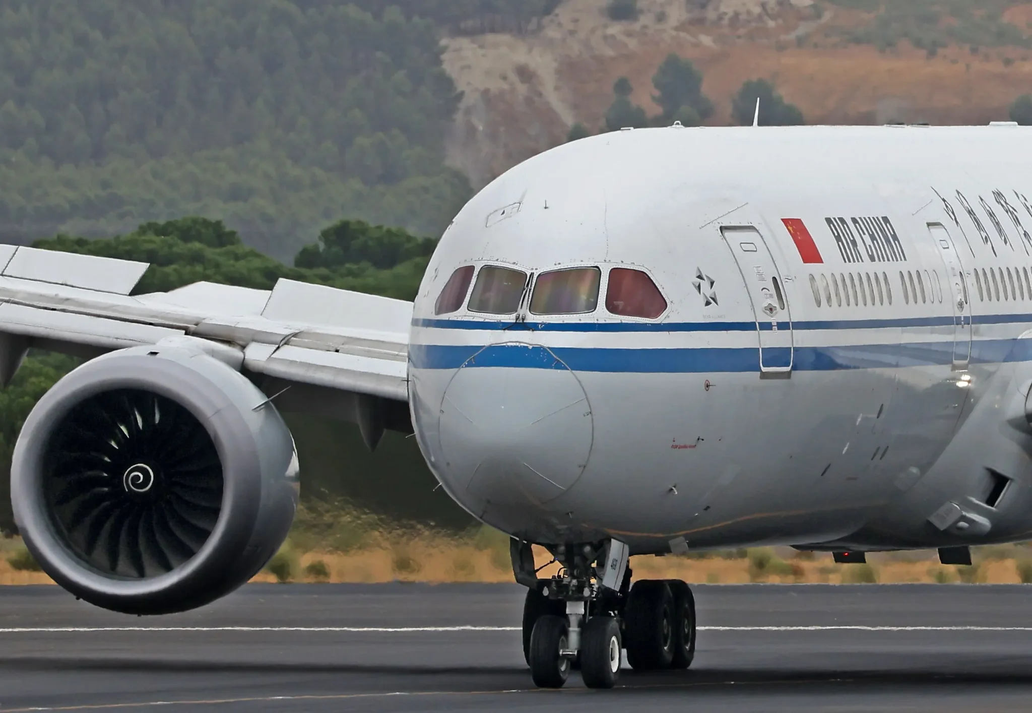 طائرة بوينغ 787 تابعة لشركة Air China على مدرج مطار، تُظهر تفاصيل المحركات والعجلات، في سياق زيارة ترامب للصين.