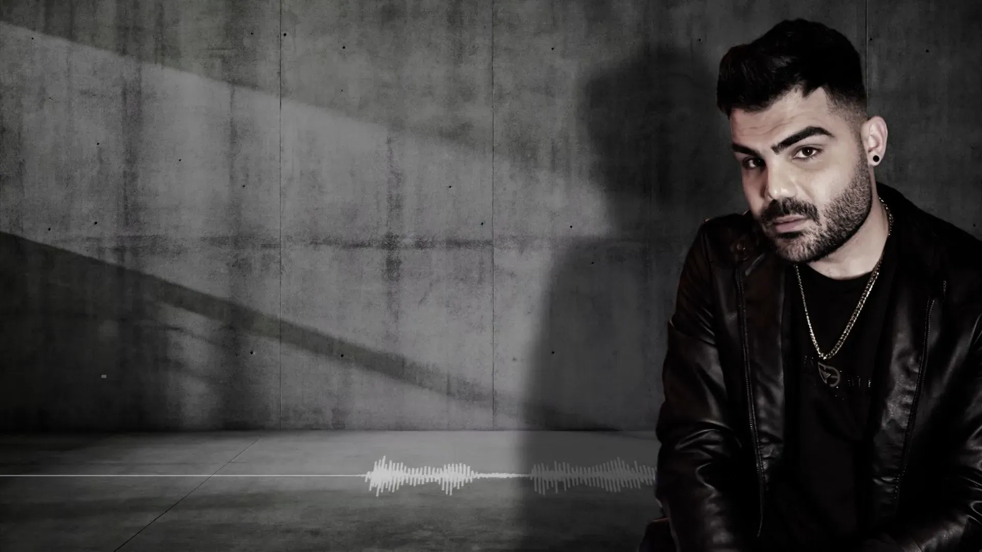 شاب يرتدي سترة جلدية يجلس في استوديو موسيقي ببرلين، يعبر عن معاناته بعد التعذيب والسجن في إيران.