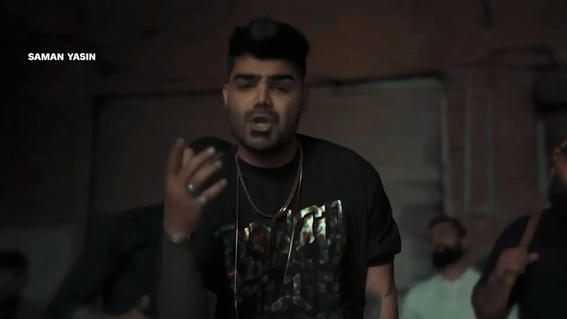 سامان ياسين، مغني الراب الإيراني الكردي، يؤدي أغنية في استوديو موسيقي في برلين، معبرًا عن معاناته وتجربته من التعذيب في السجون الإيرانية.
