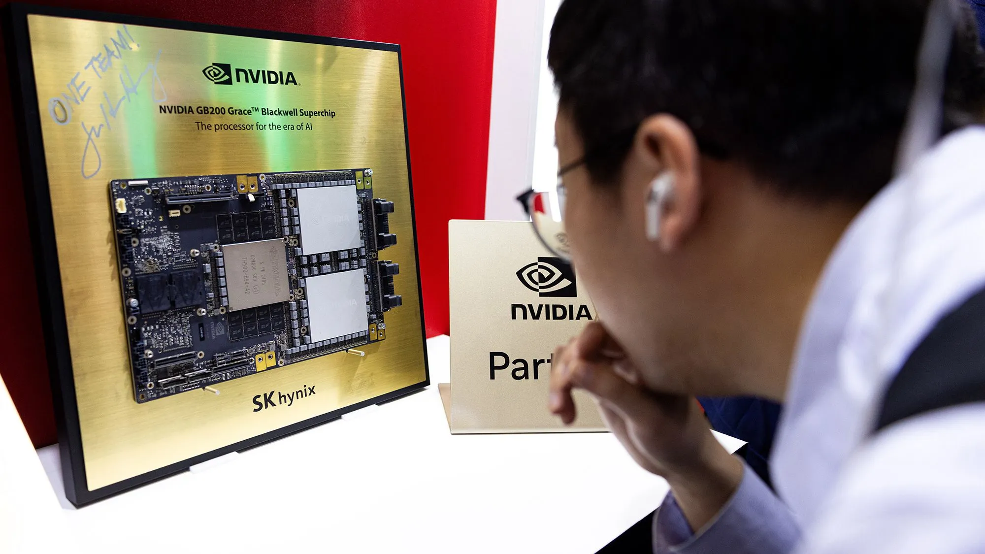 شاب يراقب شريحة معالج Nvidia Grace Blackwell المتطورة لتسريع الذكاء الاصطناعي، مع شعار SK Hynix وكلمة "شراكة" ظاهرة.